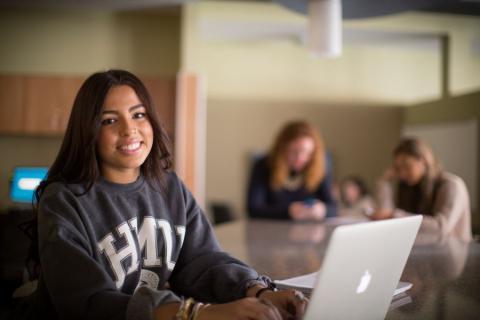 Student smiling and working on laptop