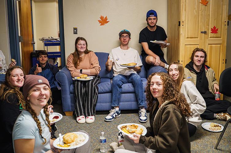 students sitting together on a couch and the floor for a meal