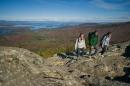 Three young people on rocky mountaintop with lake in background